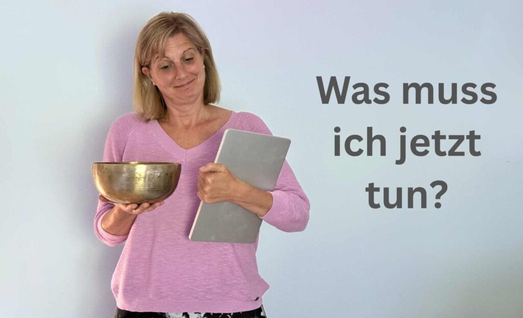 Woman in pink sweater holding a large brass bowl and a tablet, looking thoughtful, with German text 'Was muss ich jetzt tun?' on the right.